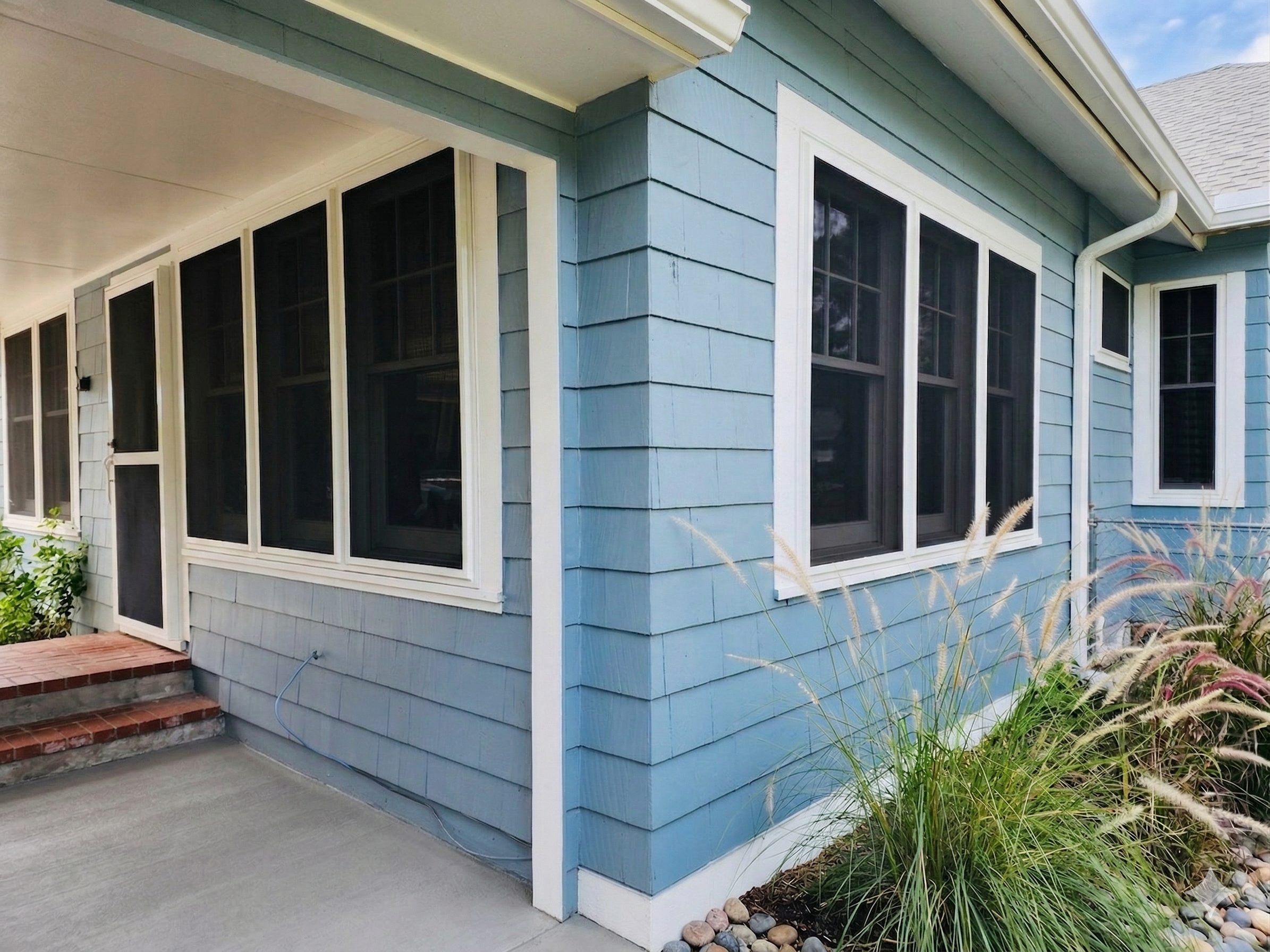 Blue Florida home with Fortress hurricane and security screens installed on its windows
