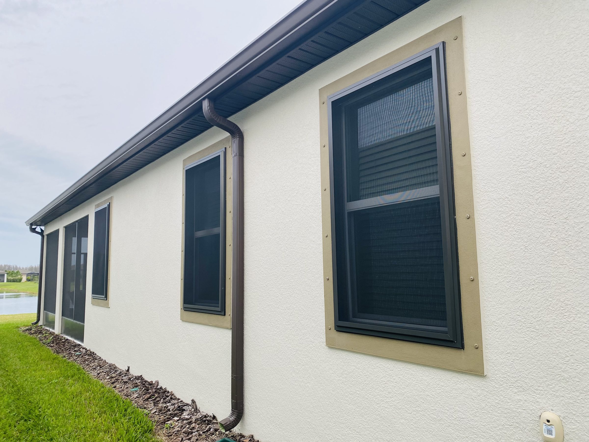 Sun-exposed stucco Florida home with bronze-framed Fortress screens installed on its windows