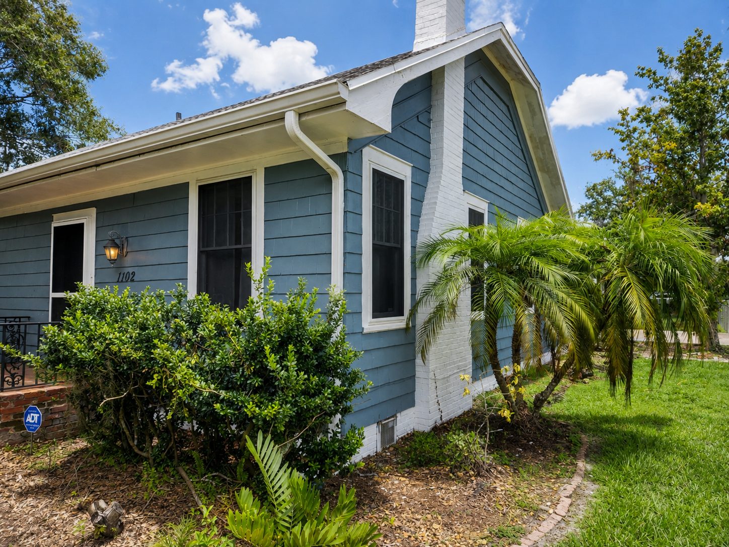 Blue single-story Florida home with dark Fortress security screens installed on its windows and entry