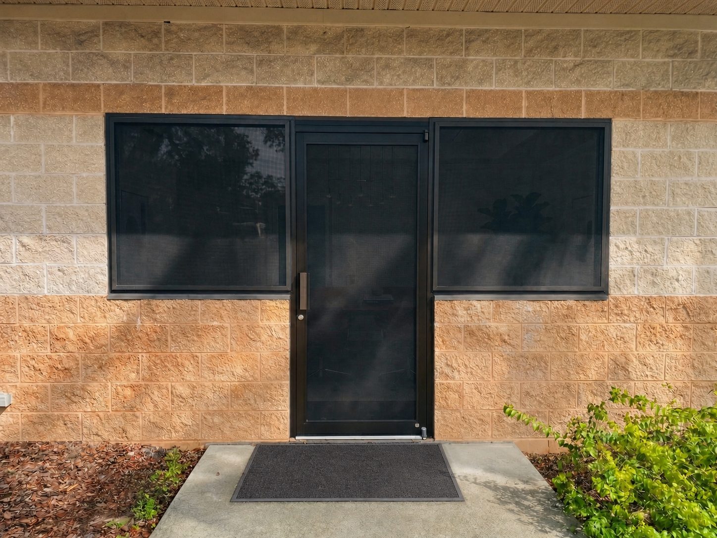 Commercial entrance with dark Fortress screens installed on the door and adjacent windows