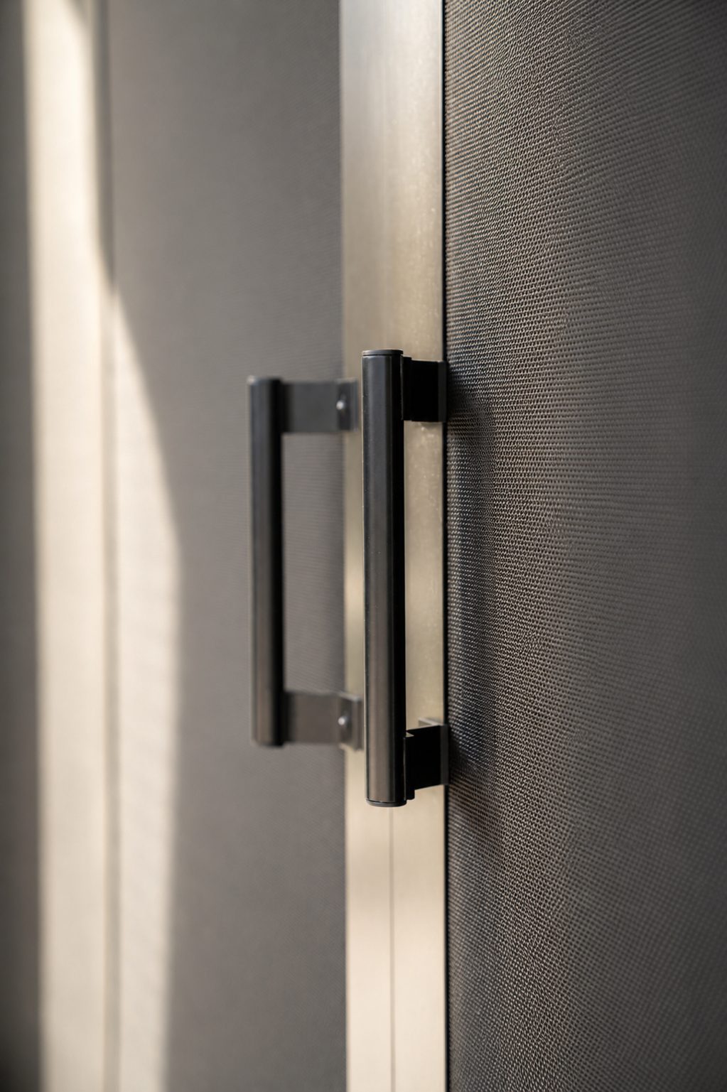 Close-up of black pull handles mounted on dark Fortress security screen panels