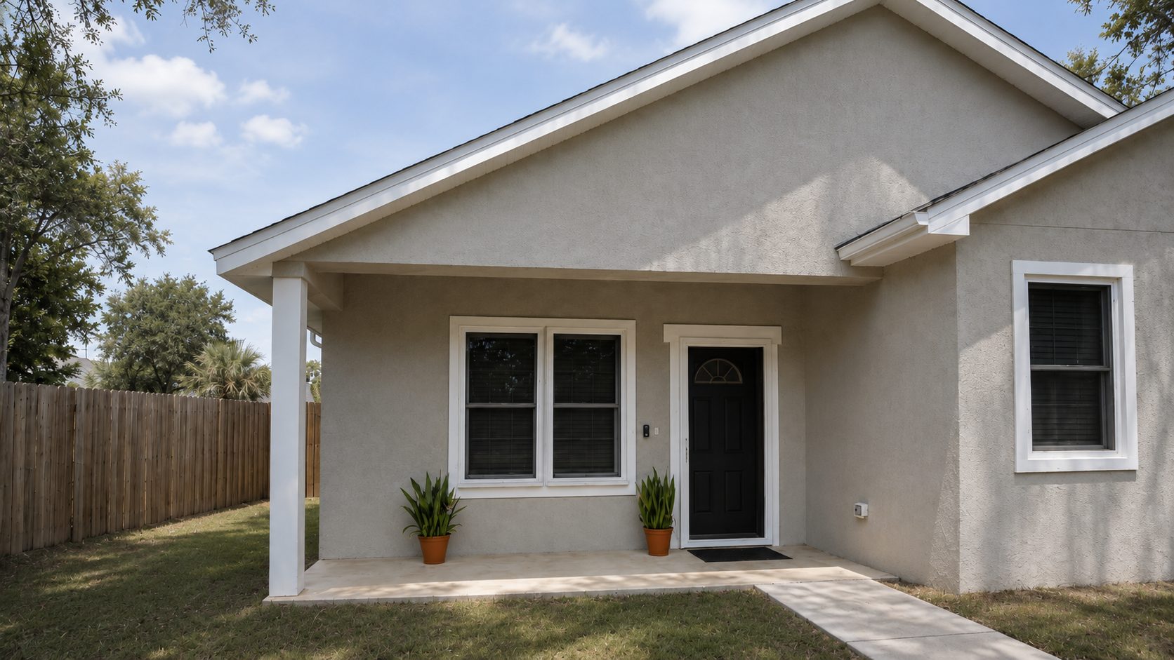 Single-story stucco home with dark Fortress security screens installed on the front windows