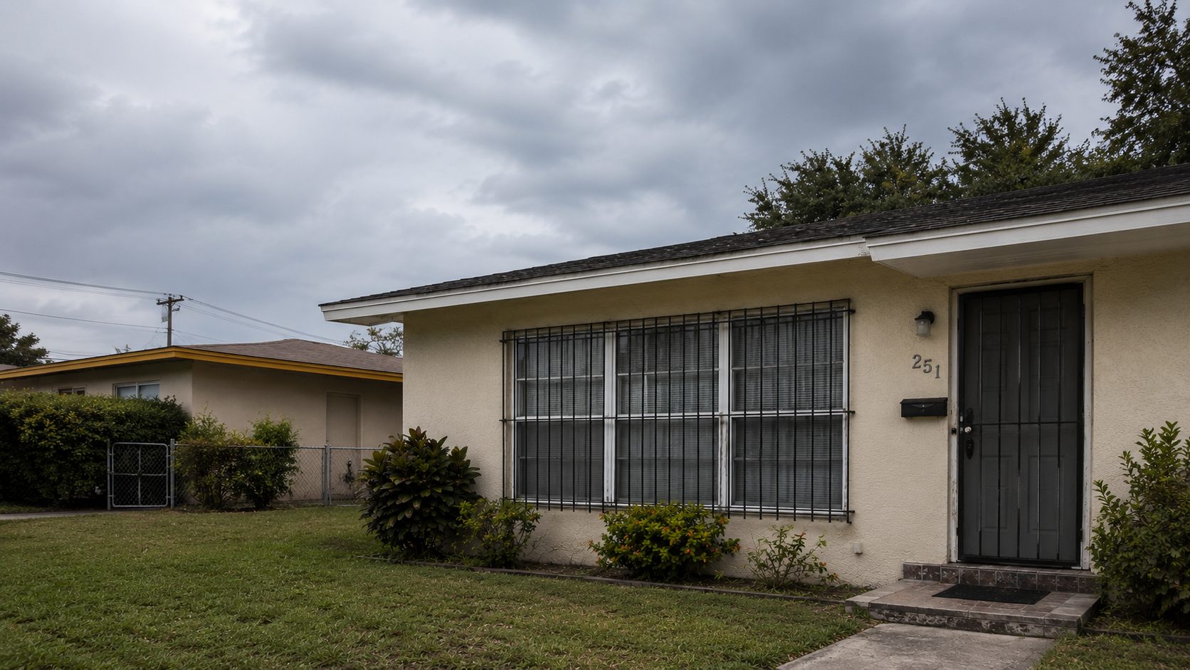 Single-story stucco home with black metal security bars across the front windows