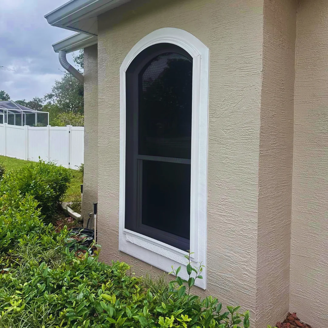 Arched residential window fitted with a dark Fortress screen