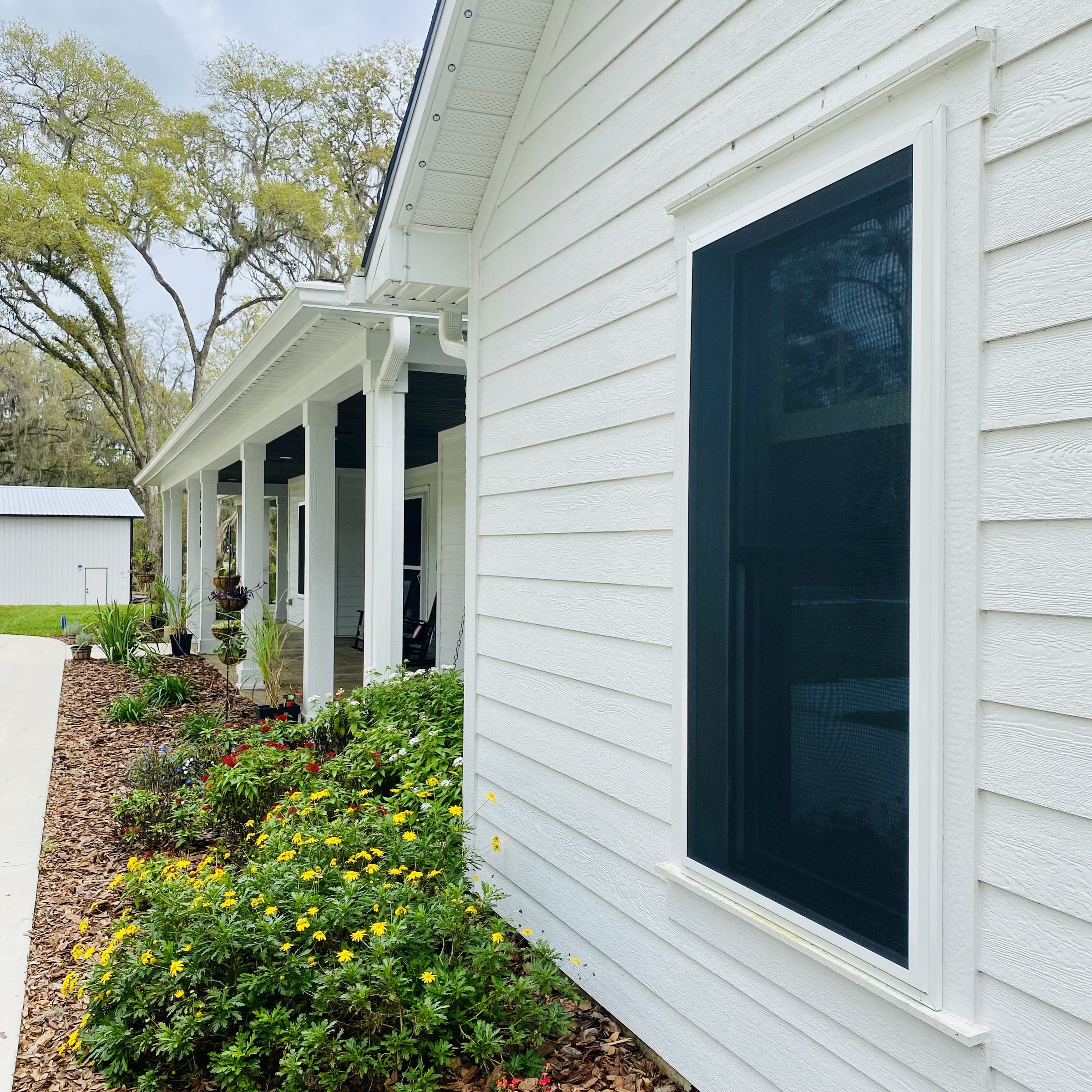 White farmhouse exterior with a dark Fortress screen installed on a window
