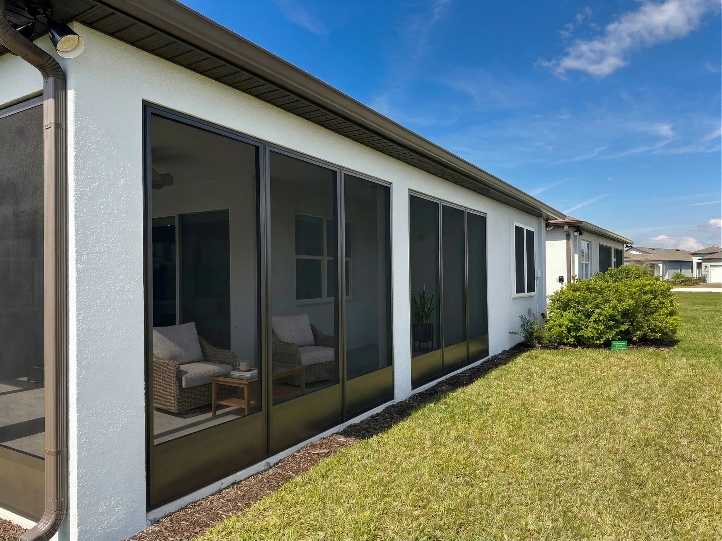 Screened porch enclosure across the rear of a white Florida home
