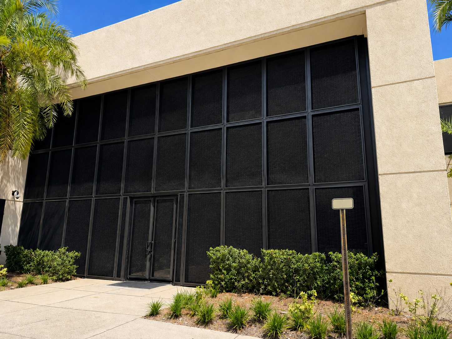Commercial facility with dark Fortress screens installed across the front window wall